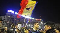 Salah satu pengunjuk rasa mengibarkan bendera Rumania berlubang hitam besar saat demo di Kota Bucharest. ( Salah satu pengunjuk rasa mengibarkan bendera Rumania berlubang hitam besar saat demo di Kota Bucharest. (www.theguardian.com)