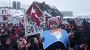 Mereka menolak ancaman aneksasi pulau Arktik tersebut. Tampak dalam foto, seorang anak laki-laki memegang peta Greenland yang dicoret dan dihiasi dengan wig yang melambangkan Presiden AS Donald Trump, selama unjuk rasa di depan konsulat AS di Nuuk, Sabtu 17 Januari 2026. (AP Photo/Evgeniy Maloletka)