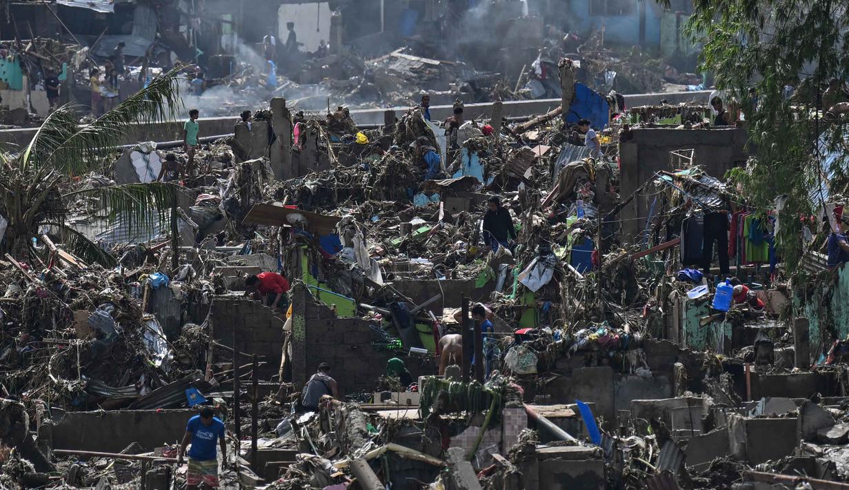 Warga membersihkan rumah-rumah mereka yang rusak akibat terjangan Topan Kalmaegi di Talisay, Provinsi Cebu, Filipina pada Rabu 5 November 2025. Di Provinsi Cebu, Filipina, warga yang paling terdampak mulai membersihkan rumah dan tempat usaha mereka yang hancur akibat banjir terburuk dalam sejarah.  (Jam STA ROSA/AFP)
