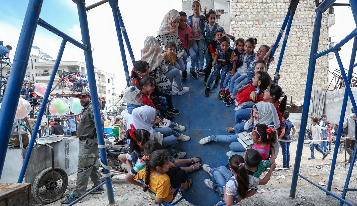 Anak-Anak Suriah Rayakan Idul Fitri di Taman Bermain: Anak-anak Suriah bermain di taman hiburan sementara ketika merayakan Idul Fitri di kota Idlib, Senin (24/5/2020). Anak-anak itu menikmati permainan yang mungkin jarang mereka rasakan di tengah peperangan yang masih berkecamuk. (OMAR HAJ KADOUR/A