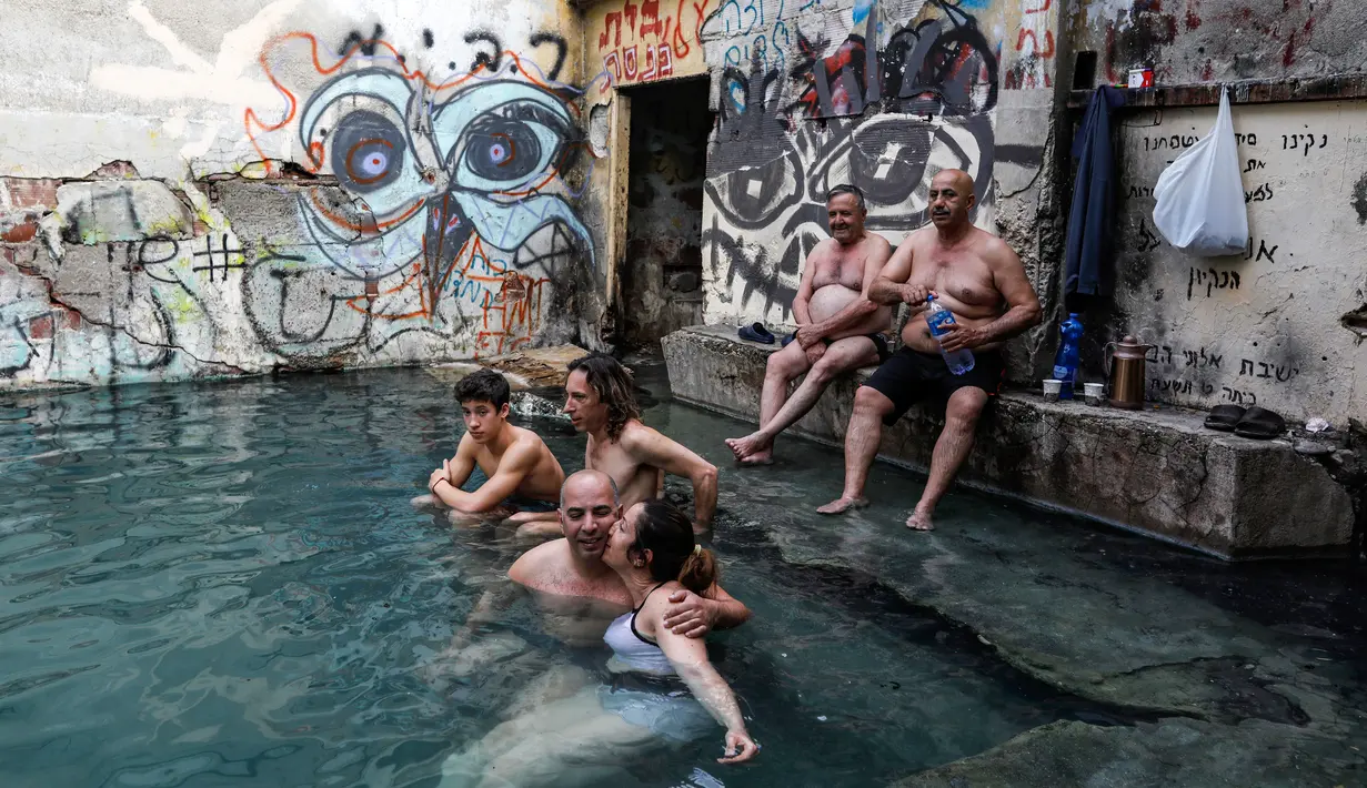 Wisatawan bersantai di kolam air panas di ujung selatan Dataran Tinggi Golan yang dianeksasi Israel, dekat perbatasan dengan Yordania, 1 Maret 2019. Kolam dengan air panas itu berasal dari aliran pipa pengeboran di Lembah Hula. (MENAHEM KAHANA/AFP)