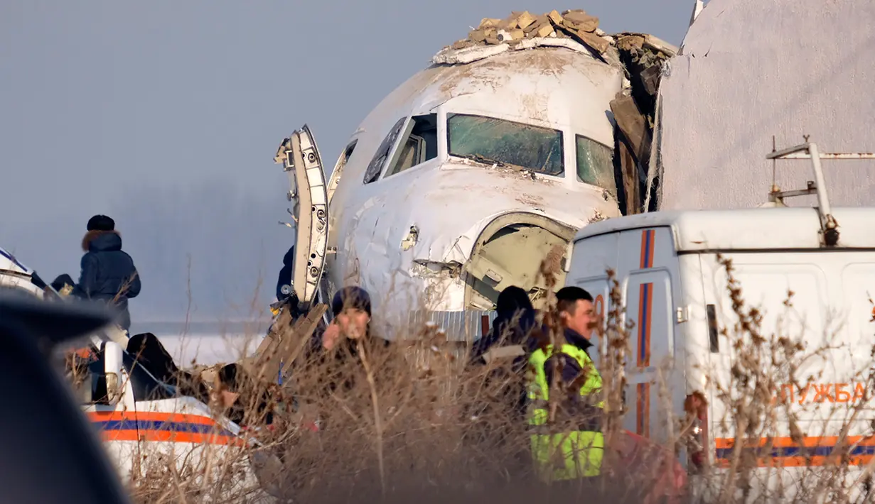 Polisi berjaga saat petugas penyelamat mengevakuasi korban jatuhnya pesawat maskapai Bek Air di dekat Bandara Almaty, Kazakhstan, Jumat (27/12/2019). Sebuah komite khusus bakal dibentuk untuk menyelidiki penyebab kecelakaan tersebut. (AP Photo/Vladimir Tretyakov)