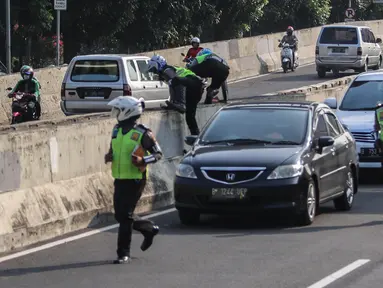 Petugas polisi lalu lintas (polantas) mengejar pengendara sepeda motor  yang melintasi JLNT Kampung Melayu-Tanah Abang, Jakarta, Selasa (25/7). Sepeda motor dilarang melintas di JLNT tersebut karena merupakan jalur cepat. (Liputan6.com/Faizal Fanani)