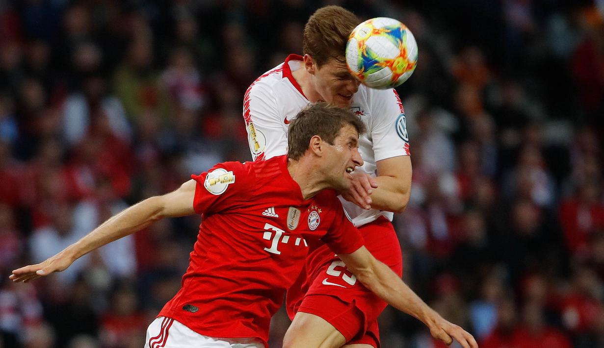 Striker Bayern Munchen, Thomas Mueller, duel udara dengan bek RB Leipzig, Marcel Halstenberg, pada laga DFB Pokal di Stadion Olympic, Berlin, Sabtu (25/5). Munchen menang 3-0 atas Leipzig. (AFP/Odd Andersen)