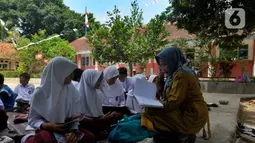 Guru saat mengajar di halaman sekolah di SDN Sukagalih, Kampung Benda, Desa Mekargalih, Kecamatan Cikalong Kulon, Cianjur Senin (29/8/2022). Akibat tiga ruangan kelas rusak berat dan terancam ambruk, sejumlah murid terpaksa belajar di halaman dan musholla sejak awal pembelajaran tatap muka Juli kemarin. (merdeka.com/Arie Basuki)