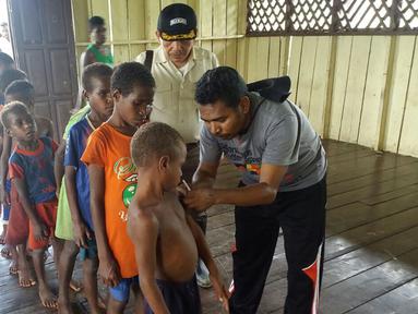 Satgas Kesehatan TNI memberi vaksin campak terhadap anak-anak di Kabupaten Asmat, Papua, Jumat (19/1). Tim Gabungan Satgas Kesehatan TNI KLB menyalurkan bantuan berupa vaksin ke kampung-kampung terpencil di Kabupaten Asmat. (LIputan6.com/Pool/Puspen TNI)