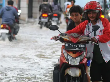 Pengendara mendorong motornya melintasi banjir di Jalan Benteng,  Duta Kranji, Kalibaru, Bekasi, Jawa Barat, Jumat (24/2/2023). Hujan yang turun di Bekasi sejak Kamis malam mengakibatkan sejumlah wilayah di Bekasi tergenang hingga lebih dari 50 cm. (merdeka.com/Imam Buhori)