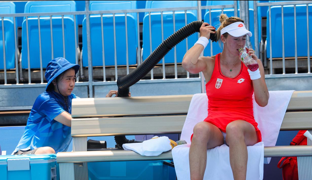Petenis Serbia Nina Stojanovic mendinginkan tubuhnya dengan mesin pendingin dalam pertandingan tenis putaran pertama tunggal putri Olimpiade Tokyo 2020 melawan Nao Hibino di Ariake Tennis Park, Tokyo, Sabtu (24/7/2021). (Foto: AFP/Giuseppe Cacace)