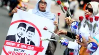 Perempuan Gerakan Masyarakat (Gema) JKW4P'7 menggelar aksi bagi-bagi bunga di Bundaran HI, Jakarta, Jumat (30/5/14). (Liputan6.com/Faizal Fanani)