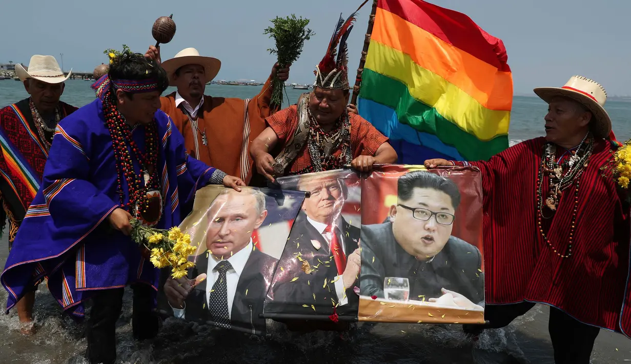 Sekelompok dukun memegang poster Presiden AS Donald Trump, Pemimpin Korut Kim Jong-un, Vladimir Putin dan Presiden Meksiko Andres Manuel Lopez Obrador selama ritual untuk menyambut tahun baru  di pantai Agua Dulce, Lima, Kamis (27/12). (AP/Martin Mejia)