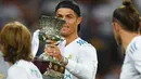 Striker Real Madrid, Cristiano Ronaldo, memegang trofi Piala Super Spanyol 2017 setelah mengalahkan Barcelona di Stadion Santiago Bernabeu, Rabu (16/8/2017). Cristiano Ronaldo meraih gelar pemain terbaik FIFA 2017. (AFP/Gabriel Bouys)