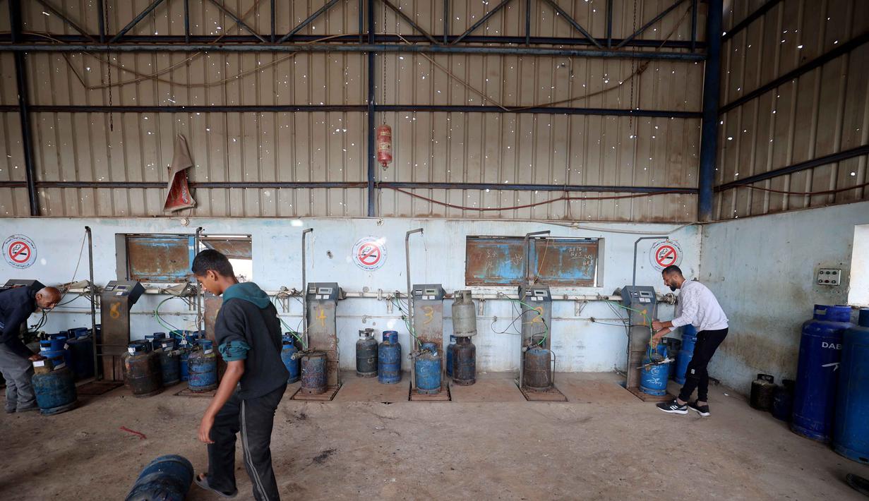 Sebelumnya, selama hampir tujuh bulan terakhir, Jalur Gaza mengalami krisis parah akibat kekurangan bakar bahan gas untuk memasak menyusul penutupan total penyeberangan oleh Israel sejak Maret 2025 lalu. Tampak dalanm foto, pekerja Palestina mengisi tabung gas di stasiun pengisian resmi di kamp pengungsi Nuseirat, di bagian tengah Jalur Gaza, pada 10 November 2025. (Eyad Baba/AFP)
