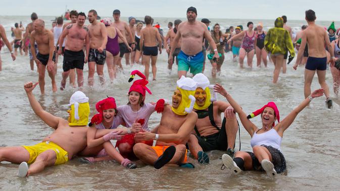 Orang-orang dengan kostum warna-warni menyerbu perairan Laut Utara  untuk merayakan akhir pekan pertama Januari 2020 di Ostend, Belgia, Sabtu (4/1/2020). Cuaca dingin tak menghalangi mereka untuk menceburkan diri ke laut yang merupakan salah satu tradisi tahun baru.  (NICOLAS MAETERLINCK/BELGA/AFP)
