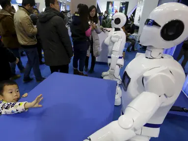 Seorang saat melihat Robot yang berbentuk mirip manusia yang bernama Robot KINGER pada Pameran Dunia Robot selama Konferensi Robot Dunia di Beijing, Cina,  (24/11). Konferensi robot ini diadakan selama tiga hari dari senin lalu. (REUTERS/Jason Lee)
