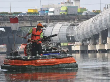 Petugas Unit Penanganan Sampah Badan Air Dinas Lingkungan Hidup (UPS Badan Air Dinas Lingkungan Hidup) menggunakan perahu yang terbuat dari botol plastik bekas di aliran Kali Ancol Jalan Martadinata, Jakarta Utara, Rabu (22/5/2024). (merdeka.com/Imam Buhori)