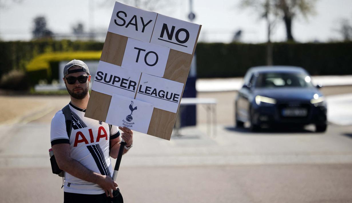 Seorang penggemar Tottenham Hotspurs memegang spanduk anti Liga Super Eropa di luar tempat latihan, London, Senin (19/4/2021). (Foto: AFP/Tolga Akmen)