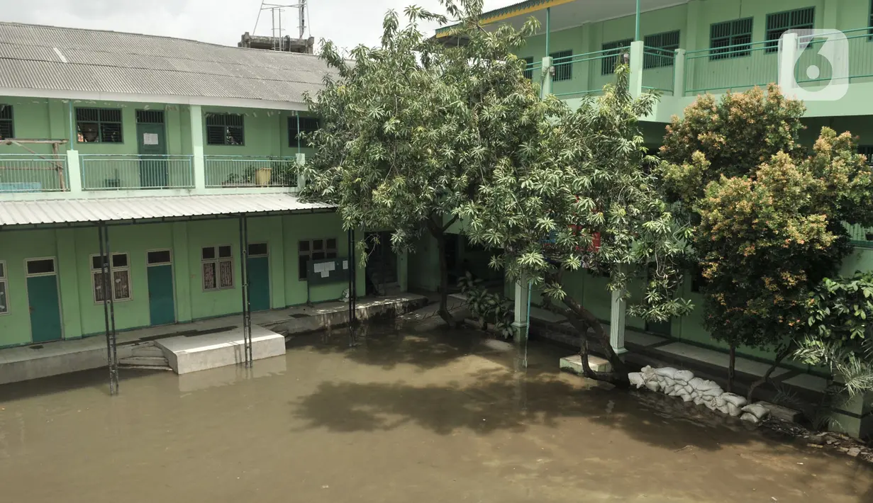 Kondisi banjir yang masih menggenangi gedung Madrasah Tsanawiyah (MTs) Nur Attaqwa, Pegangsaan Dua, Kelapa Gading, Jakarta Utara, Senin (24/2/2020). Banjir yang terjadi sejak Minggu (23/2) kemarin mengakibatkan kegiatan belajar di MTs itu terpaksa diliburkan sementara. (merdeka.com/Iqbal S Nugroho)