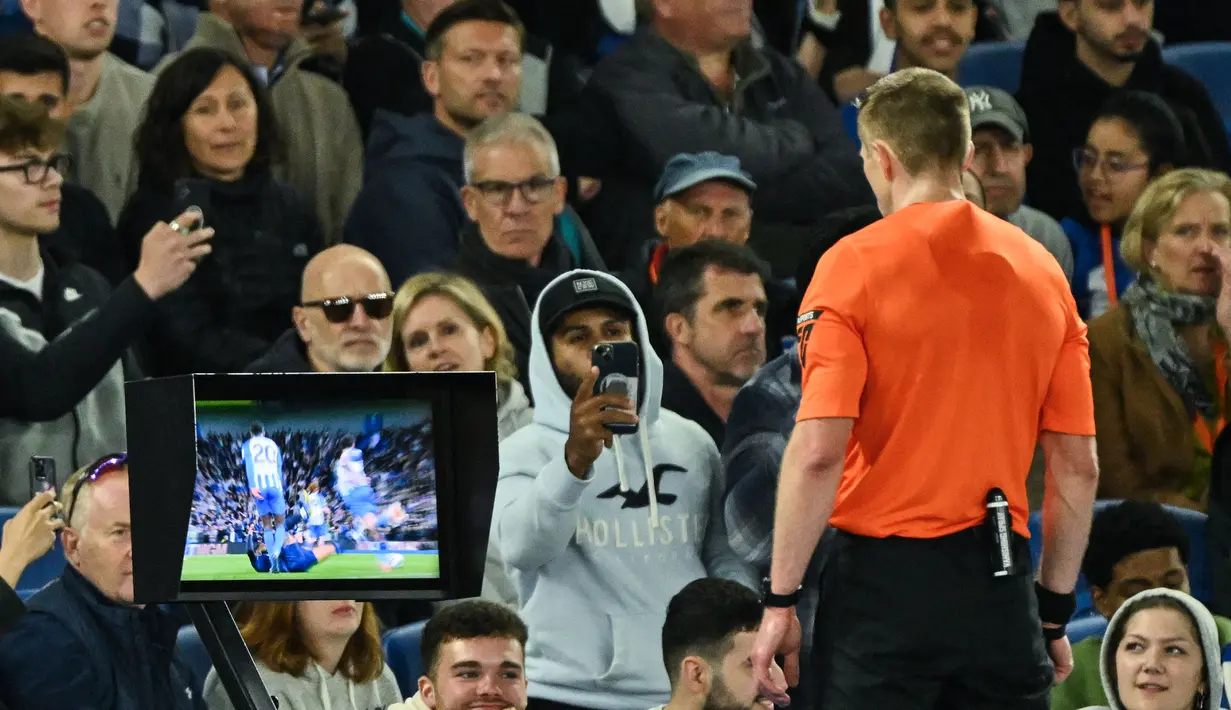 Wasit Michael Salisbury memeriksa rekaman VAR sebelum memutuskan memberi kartu merah kepada bek Chelsea, Reece James saat menghadapi Brighton and Hove Albion pada laga tunda pekan ke-34 Liga Inggris 2023/2024 di American Express Community Stadium, Brighton, Rabu(15/5/2024). (AFP/Glyn Kirk)