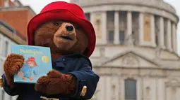 Seseorang yang mengenakan kostum Paddington Bear berpose sambil menunjukkan buku di London, Inggris (30/5). Sesi foto ini untuk mempromosikan peluncuran buku terakhir Michael Bond, Paddington di St Paul's. (AP/Frank Augstein)