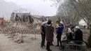 Warga berkumpul di dekat reruntuhan usai diguncang gempa di Desa Kuzigun di Taxkorgan County, wilayah Otonomi Xinjiang Uygur, China, (11/5). Gempa berkekuatan 5,5 skala Richter  terjadi pukul 05.58 waktu setempat. (Li Jing / Xinhua via AP)