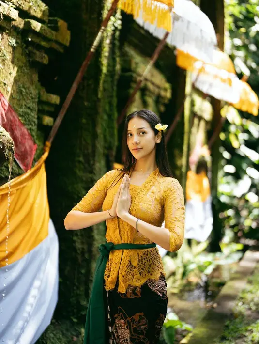 <p>Saat melakukan upacara melukat di Bali, Anya menggunakan busana kebaya lengkap dengan rok batik. Brokat lace berwarna kuning yang dilengkapi dengan kain hijau di pinggang dan kain batik hitam membuatnya tampil manis. [Instagram/anyageraldine]</p>