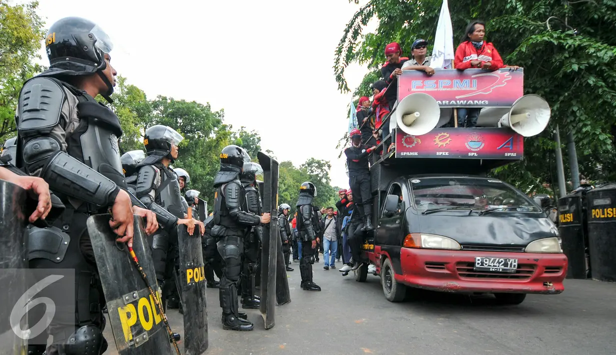 Petugas kepolisian saat menghadang ribuan buruh saat mengelar aksi di Jalan Medan Merdeka, Jakarta, Kamis (10/12). Buruh kembali melakukan aksi demonstrasi menolak PP 78 tahun 2015. (Liputan6.com/Yoppy Renato)