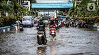 Kendaraan bermotor melintasi jalan yang tergenang air rob (banjir pasang air laut) di Kawasan Pasar Ikan Muara Baru, Jakarta, Kamis (4/6/2020). Banjir rob di Pelabuhan Muara Baru tersebut terjadi akibat cuaca ekstrem serta pasangnya air laut. (Liputan6.com/Faizal Fanani)