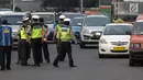 Petugas polisi mengatur lalu lintas saat pemberlakuan sistem ganjil genap di pintu masuk Gardu Tol Cibubur 2, Jakarta, Senin (16/4). Aturan ganjil genap ini diujicobakan di Gerbang Tol pada  Senin 16 April 2018. (Liputan6.com/Faizal Fanani)