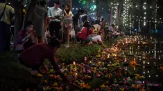 Orang-orang menghanyutkan 'krathong' untuk menandai festival Loy Krathong di sebuah danau di Bangkok, Thailand,  Senin (11/11/2019). Loy Krathong adalah ritual melarung wadah berbentuk lotus yang didalamnya diberi sesajen, lilin dan dupa. (Lillian SUWANRUMPHA / AFP)