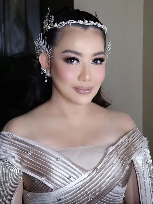 Reza Artamevia jadi fairy goddess mengenakan pleated dress dan headpiece nuansa perak yang mewah. [@rezaartameviaofficial]