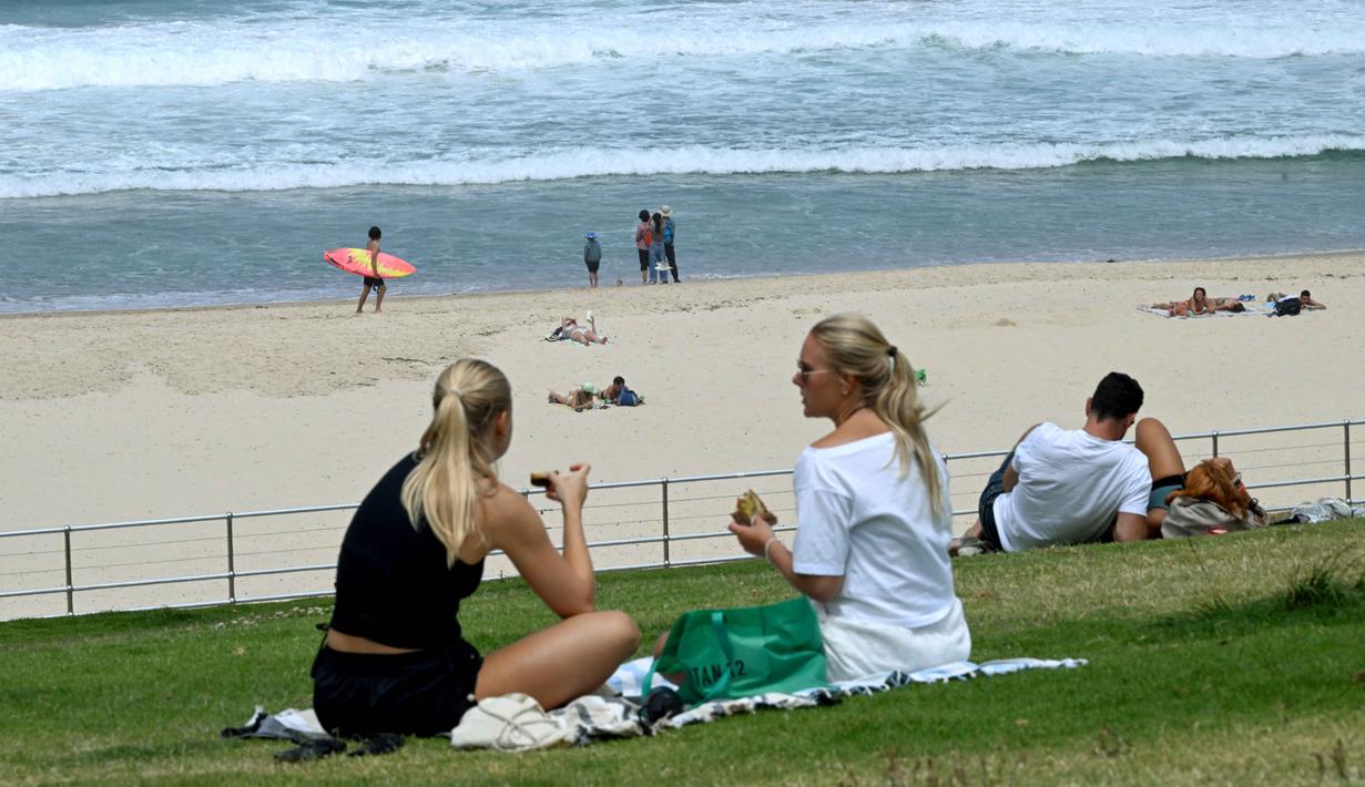 Pada Senin 15 Desember 2025 terlihat sejumlah wisatawan mulai kembali memenuhi area pantai. Bondi merupakan pantai ikonik di Sydney, Australia, yang terkenal dengan budaya selancar, sejarah, dan keindahan alamnya. Tampak dalam foto, orang-orang terlihat di Pantai Bondi di Sydney, Australia sehari setelah penembakan atau pada Senin 15 Desember 2025. (Saeed KHAN/AFP)