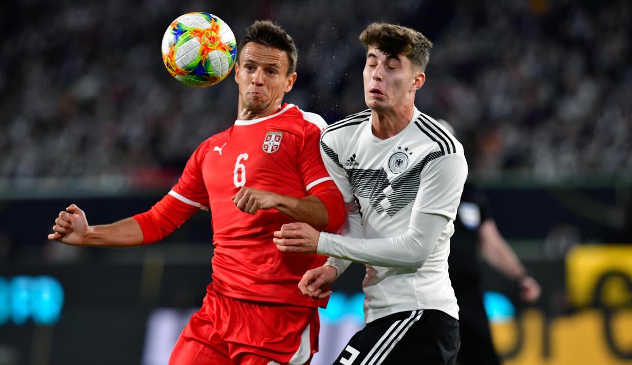 Gelandang Jerman, Kai Havertz, duel udara dengan gelandang Serbia, Nemanja Maksimovic, pada laga persahabatan di Stadion Volkswagen, Rabu, (20/3). Jerman ditahan imbang 1-1 oleh Serbia. (AFP/Tobias Schwarz)
