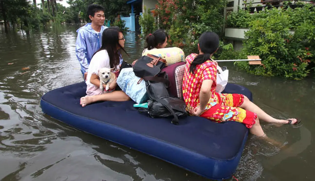 Warga menggunakan kasur karet ketika berusaha keluar dari pemukiman mereka yang terendam banjir di kawasan Periuk, Tangerang, Banten, Selasa (10/2). (ANTARA FOTO/Rivan Awal Lingga)