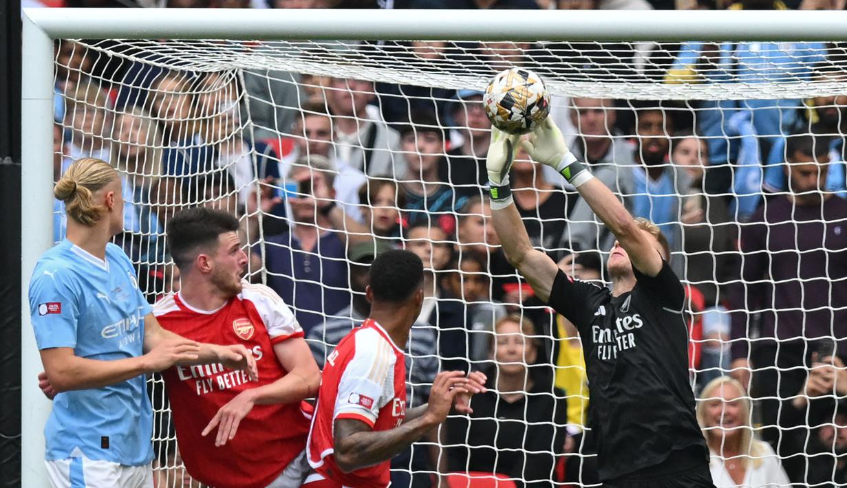 Kiper Arsenal, Aaron Ramsdale, berusaha menghalau bola saat melawan Manchester City pada laga Community Shield di Stadion Wembley, London, Minggu (6/8/2023). Arsenal mengalahkan Manchester City 4-1 lewat adu penalti setelah bermain imbang 1-1 selama 90 menit. (AFP/Glyn Kirk)