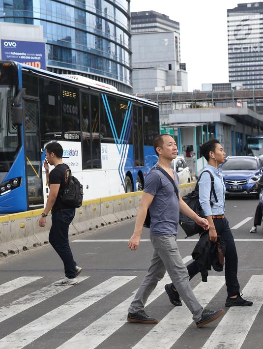 Warga menyebrang jalan Sudirman di kawasan Tosari, Jakarta, Jumat (14/12). Penggunaan pelican crossing di kawasan ini menggantikan fungsi Jembatan Penyebrangan Orang (JPO) Tosari yang akan dibongkar. (Liputan6.com/Helmi Fithriansyah)