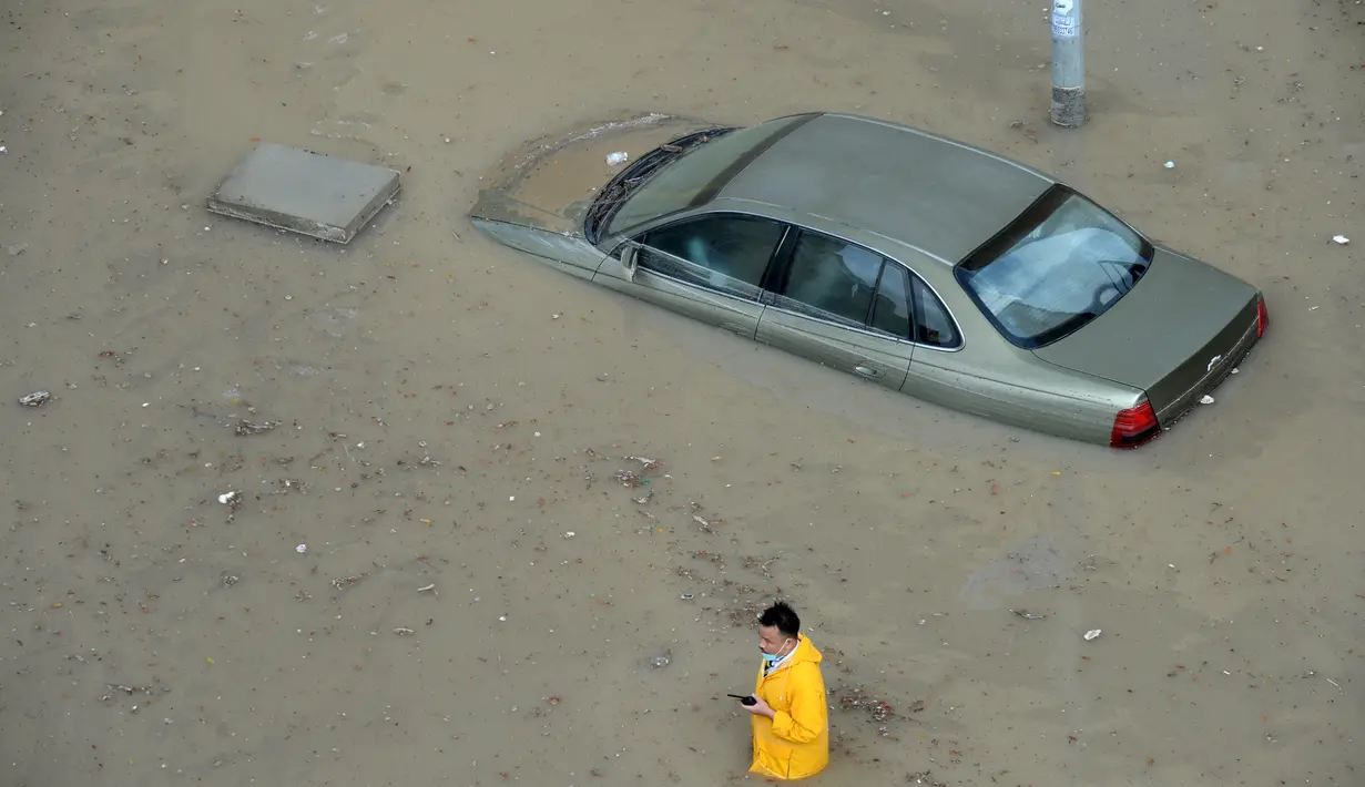 Seorang pria melintasi sebuah jalan yang terendam banjir menyusul hujan lebat di Kegubernuran Mubarak Al-Kabeer, Kuwait (29/11/2020). Hujan lebat melanda Kuwait pada Sabtu (28/11) malam dan Minggu (29/11) pagi waktu setempat. (Xinhua/Asad)