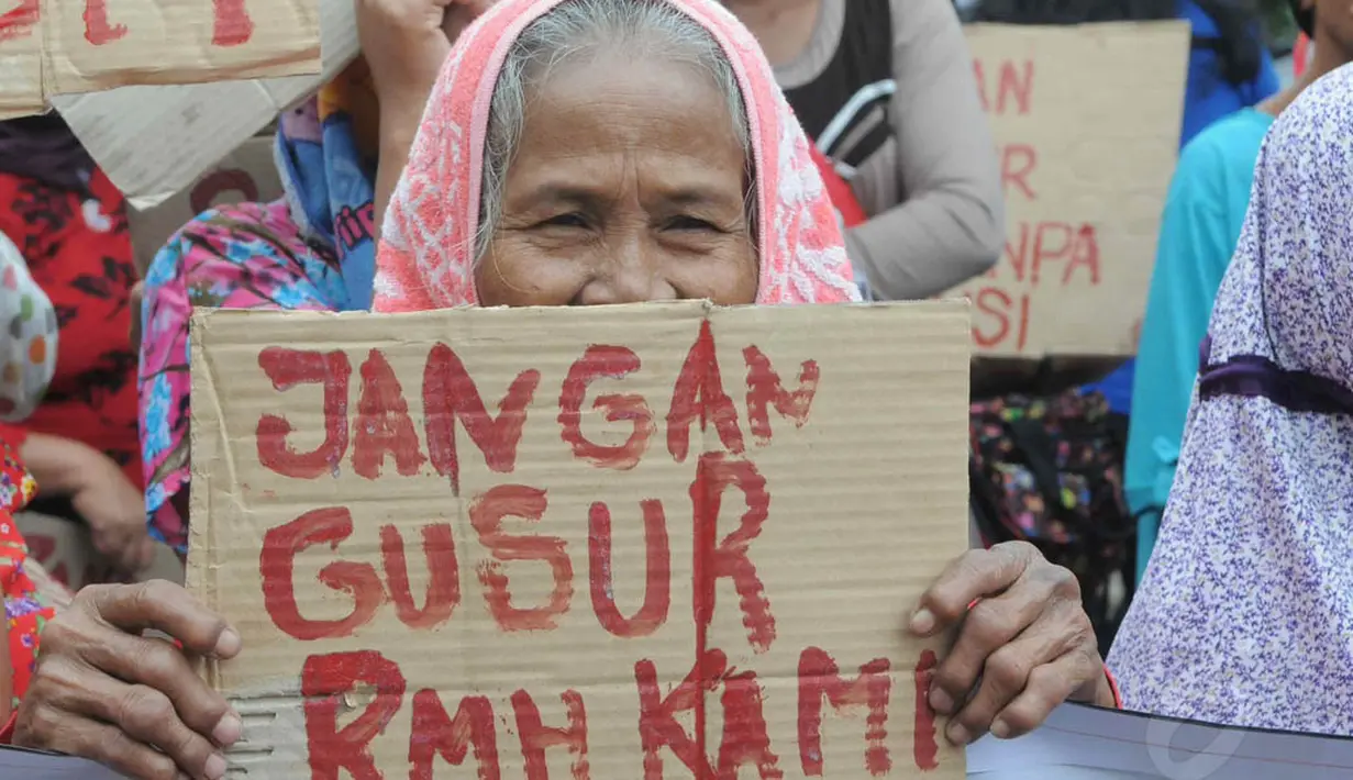Seorang wanita lansia tampak membawa lembaran karton bertuliskan "jangan gusur rumah kami" di depan Balaikota DKI Jakarta, (11/9/14). (Liputan6.com/Herman Zakharia)