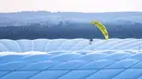 Paraglider Greenpeace terbang ke stadion sebelum pertandingan Grup F Euro 2020 antara Prancis dan Jerman di Allianz Arena, Munich, Jerman, Selasa (15/6/2021). Sang aktivis sempat mengenai peralatan spidercam. (Matthias Balk/DPA via AP)