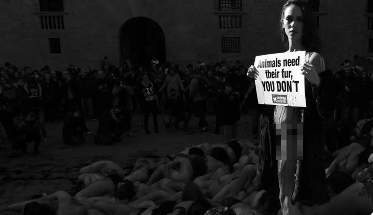 Seorang aktivis pecinta hewan membawa sebuah tulisan saat melakukan aksi bugil bersama di Barcelona, Minggu (7/12/2014). (AFP Photo/Liuis Gene)