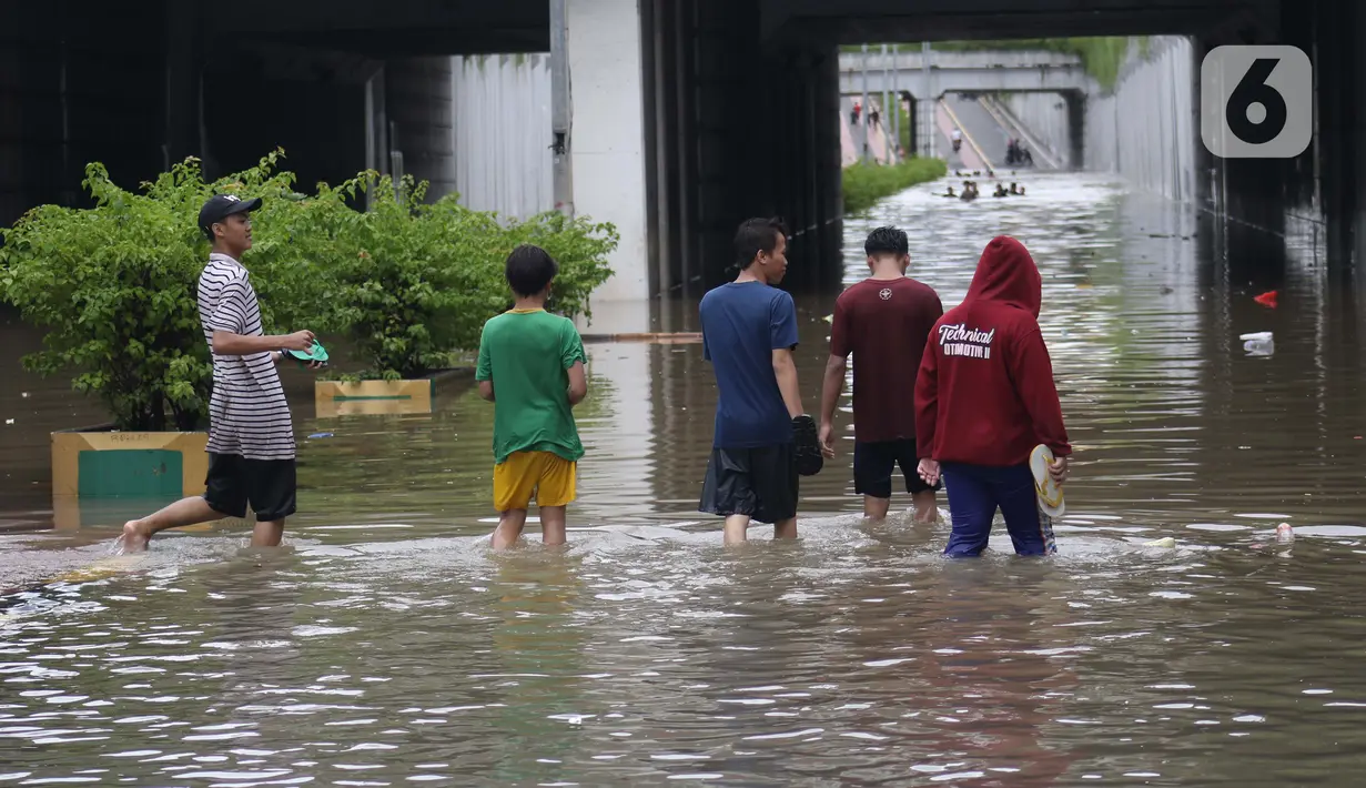 Warga melintasi banjir di terowongan Jalan Angkasa, Jakarta, Selasa (25/2/2020). Hujan yang mengguyur Jakarta sejak Senin (24/2) malam membuat sejumlah kali meluap dan menyebabkan banjir di terowongan tersebut. (Liputan6.com/Helmi Fithriansyah)