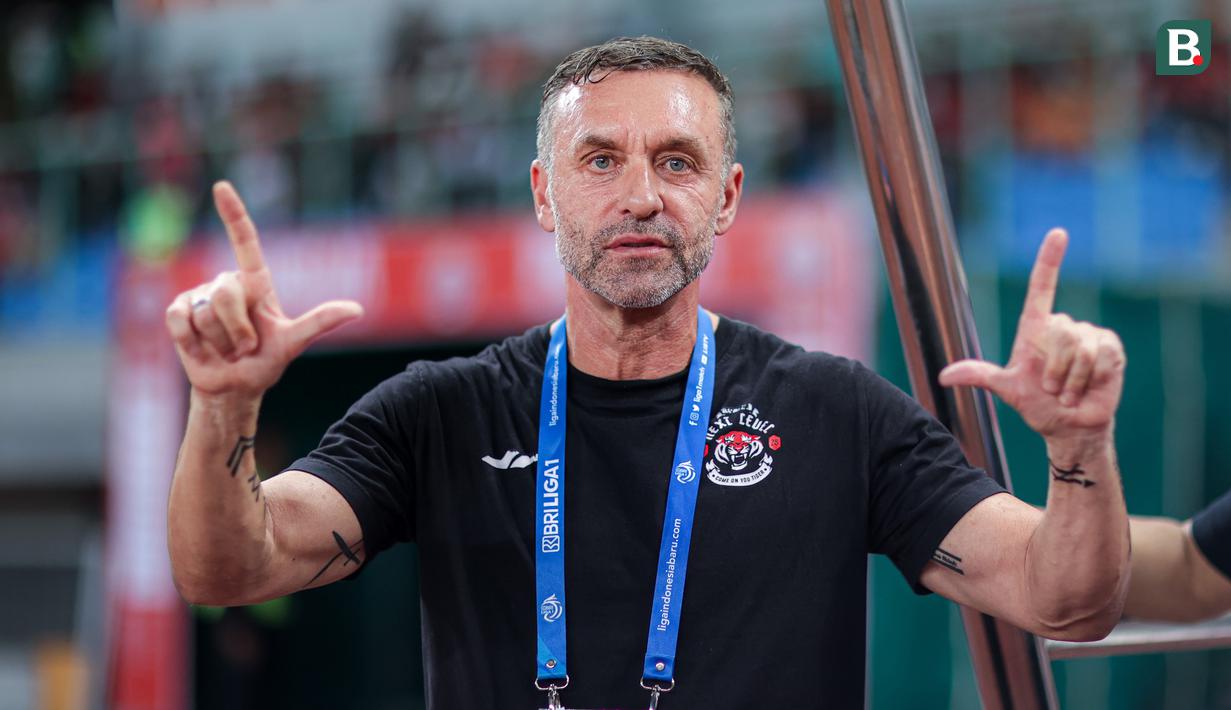 <p>Pelatih Persija Jakarta, Thomas Doll, menunjukkan lambang khas The Jak sebelum pertandingan pekan ke-23 BRI Liga 1 2023/2024 antara Persija Jakarta melawan PSS Sleman yang berlangsung di Stadion Patriot Chandra Bhaga, Bekasi, Sabtu (16/12/2023). (Bola.com/Bagaskara Lazuardi)</p>