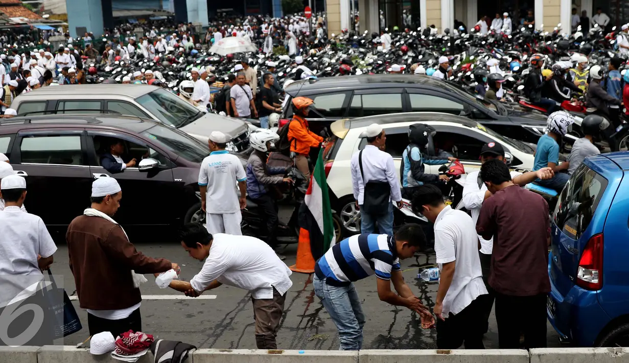 Demonstran memanfaatkan air botol untuk wudhu salat Jumat, di sekitar Halte Juanda, Jakarta, Jumat (4/11). Karena seluruh bagian masjid Istqlal penuh, sebagian massa gelar salat Jumat di sekitar Jalan Ir. H. Juanda. (Liputan6.com/Gempur M. Surya)