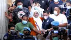 M Rizieq Shihab (tengah) mengangkat tangan saat meninggalkan gedung Ditreskrimum Polda Metro Jaya, Jakarta, Minggu dini hari (13/12/2020). Rizieq Shihab ditahan setelah menjalani pemeriksaan sebagai tersangka penghasutan dan kerumunan di tengah pandemi COVID-19. (Liputan6.com/Helmi Fithriansyah)