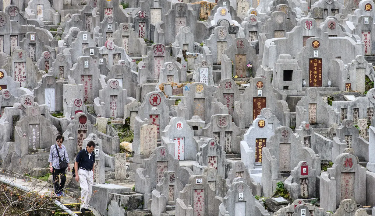 Sepasang warga mengunjungi makam kerabat saat Festival Chung Yeung atau juga dikenal Tomb Sweeping Day di sebuah pemakaman di Hong Kong, 17 Oktober 2018. Festival ini adalah hari untuk menghormati dan mengingat leluhur keluarga.  (Anthony WALLACE/AFP).