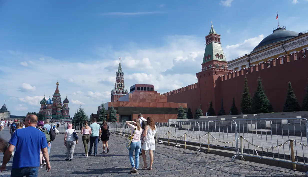 Sejumlah warga melintas di Red Square dengan tampak kanan Mauseleum Lenin dan belakang Saint Basil Cathedral. (Bola.com/Okie Prabhowo)