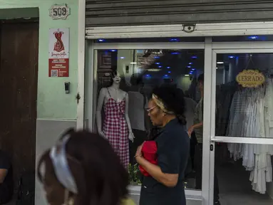 Warga berjalan melewati toko pakaian pribadi yang tutup di Havana, Kuba, Sabtu, 11 November 2023. (AP Photo/Ramon Espinosa)