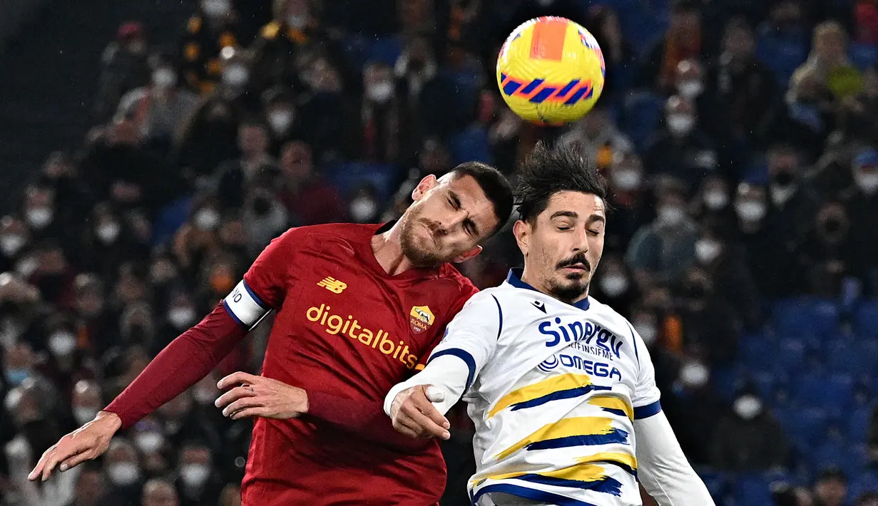 Gelandang AS Roma Lorenzo Pellegrini (kiri) melompat saat berebut bola dengan bek Hellas Verona Koray Gunter pada pekan ke-26 Liga Italia di Olimpico, Minggu (20/2/2022) dini hari WIB. AS Roma ditahan imbang Verona dengan skor 2-2. (Andreas SOLARO / AFP)