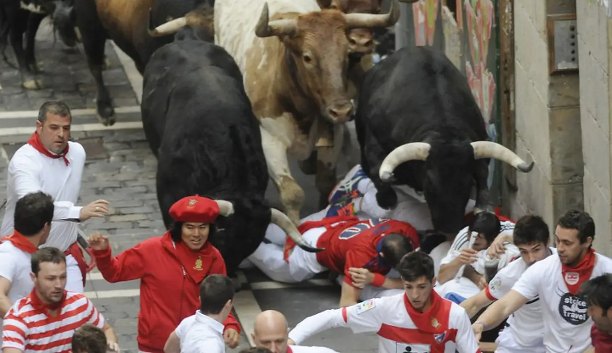 Beberapa peserta terjatuh dan terinjak oleh banteng yang berlari di Festival San Fermin di Pamplona, Spanyol (10/07/2014) (AFP PHOTO/Ander GILLENEA)