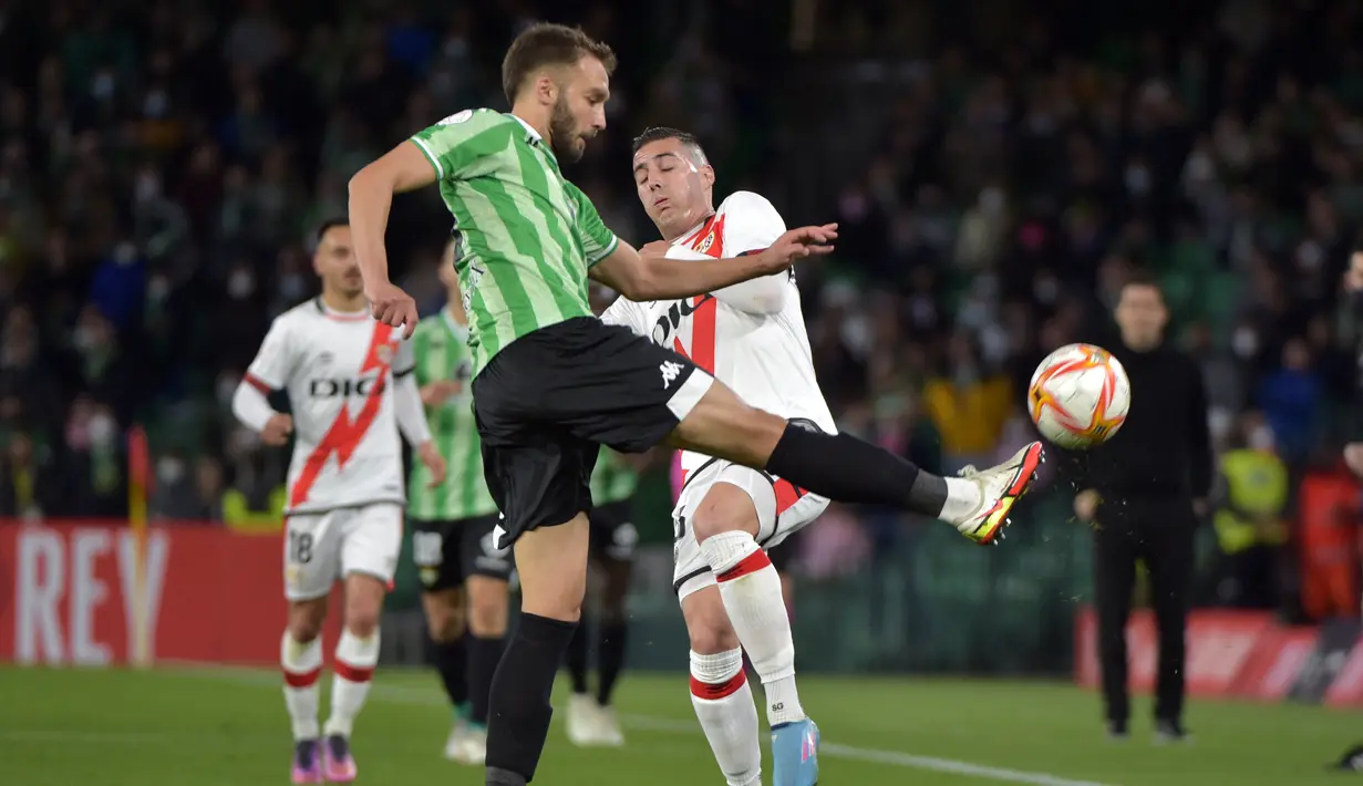 Bek Real Betis, German Pezzella (kiri) berebut bola dengan penyerang Rayo Vallecano, Sergi Guardiola pada semifinal Copa del Rey di Stadion Benito Villamarin, Spanyol (4/3/2022). Hasil imbang itu membuat Real Betis lolos ke babak final dengan agregat kemenangan 3-2. (AFP/Cristina Quicler)