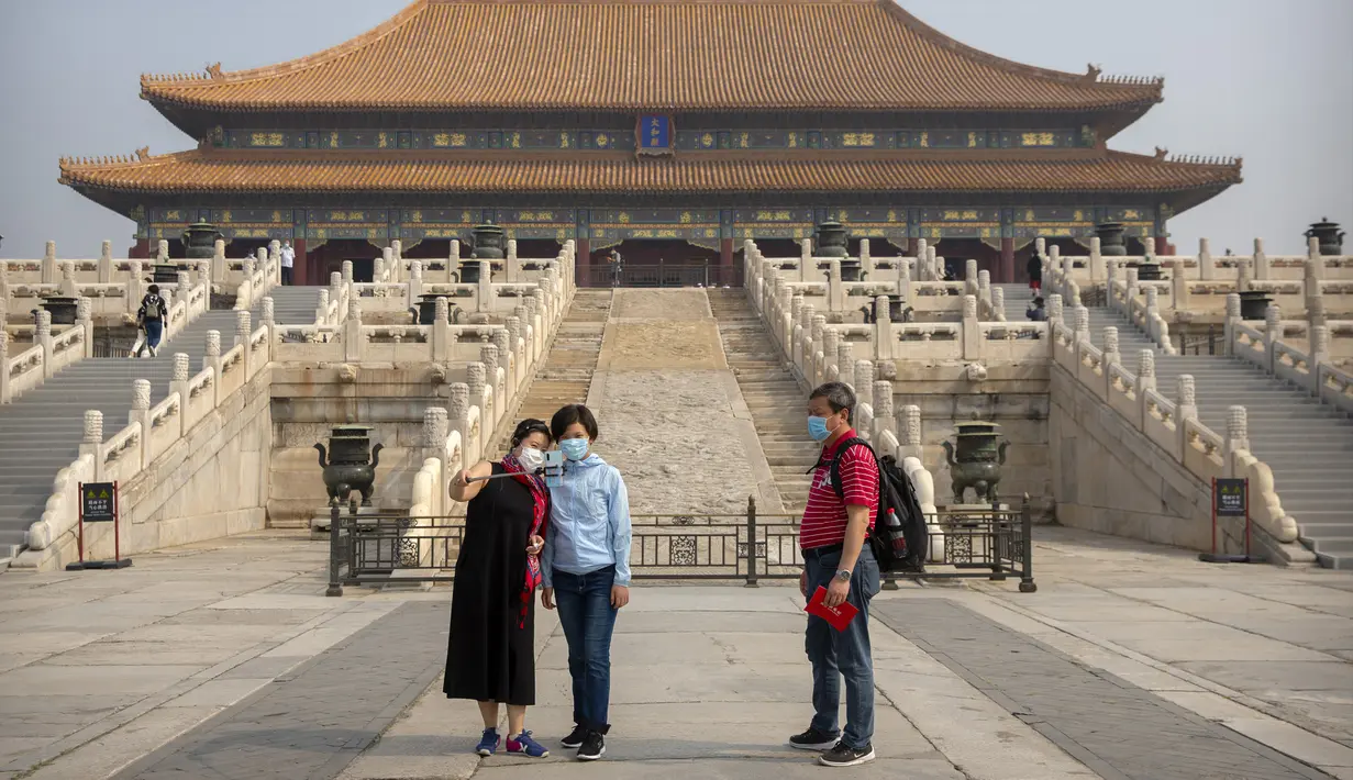 Pengunjung mengenakan masker saat berswafoto di Kota Terlarang, Beijing, China, Jumat (1/5/2020). Kota Terlarang kembali dibuka setelah ditutup lebih dari tiga bulan karena pandemi virus corona COVID-19. (AP Photo/Mark Schiefelbein)